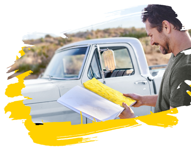 Man reading his map while standing outside next to his car