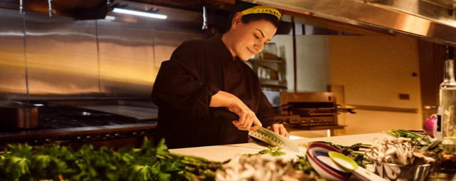 Woman cutting food in kitchen.