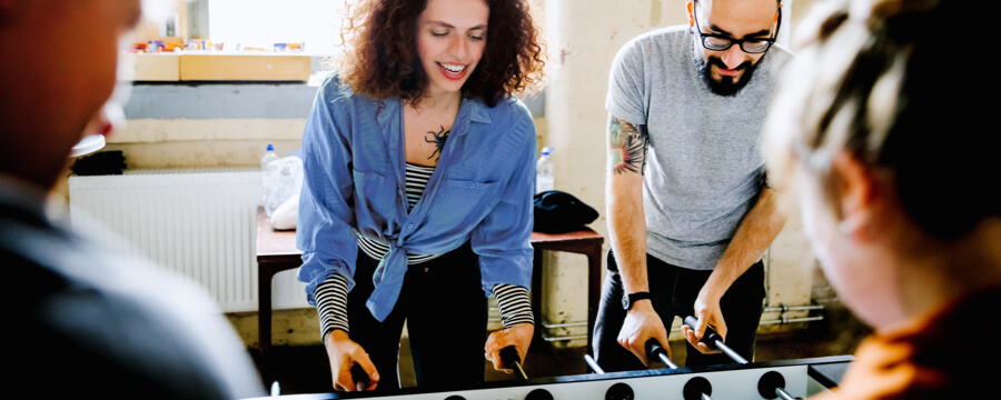 A man and woman laughing while playing foosball.