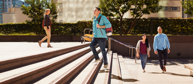 Man holding skateboard while walking up stairs.